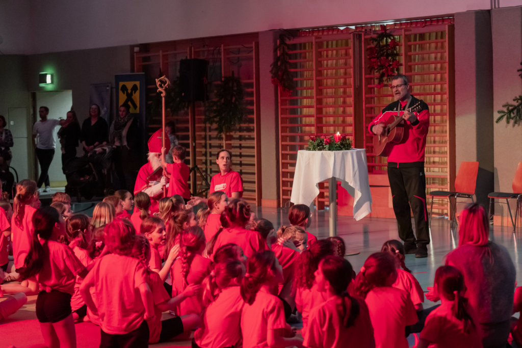 Der Nikolaus und am boden sitzende Kinder singen